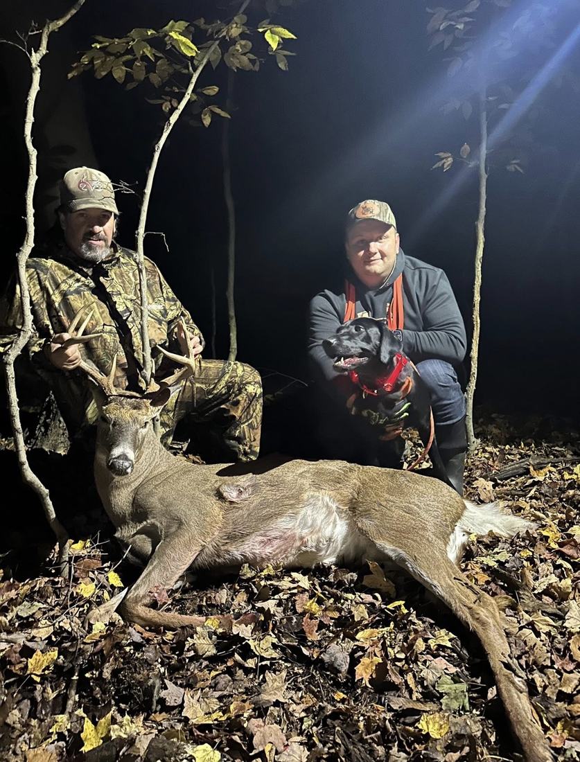 Two men and a tracking dog with a recovered buck at night